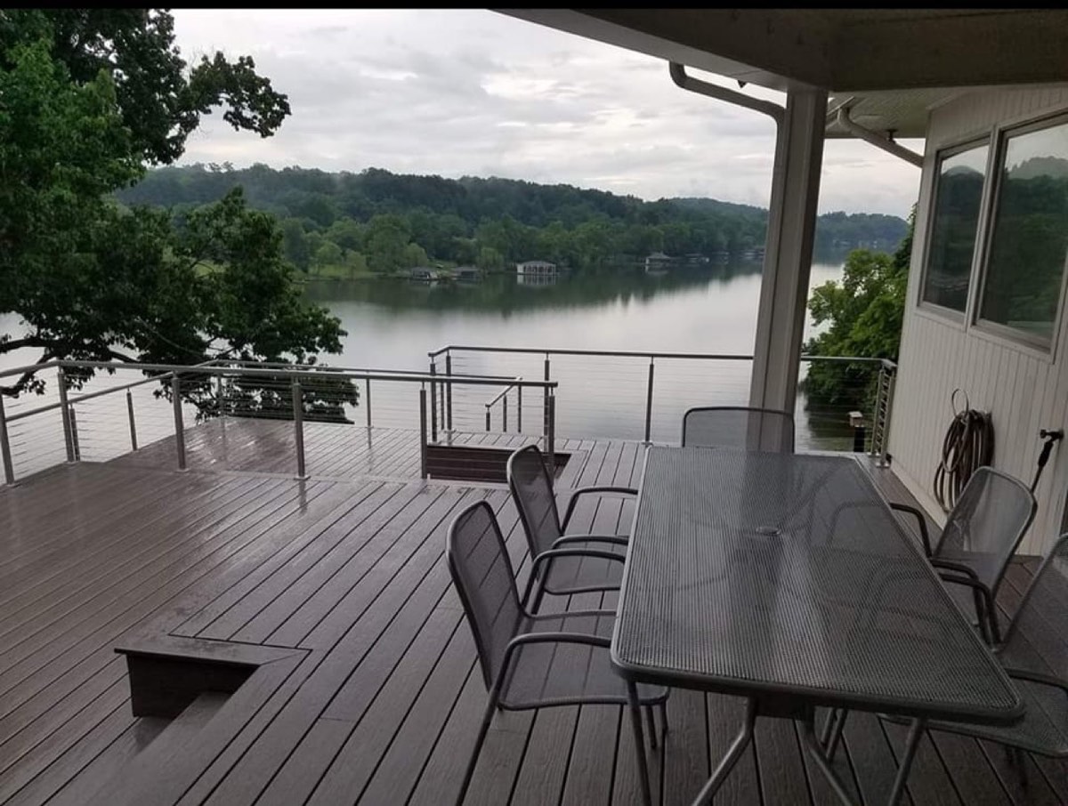 New wood deck construction with custom railing on brick home